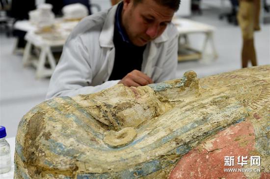 一名专家在大埃及博物馆木制品研究室内修复木棺