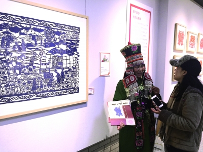 參加中央美院研修研習培訓的學員在結業展上向觀眾講述自己的剪紙作品
