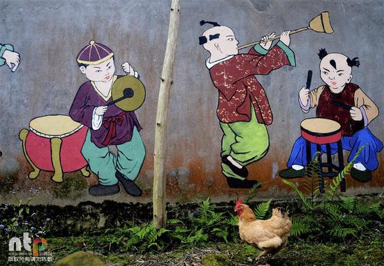 《欢乐鸡年》：2017年2月21日，福建省南平市。鸡年里，涂鸦迎春之画面，似乎正好吸引住一只鸡的到来。新通图/光影可人处