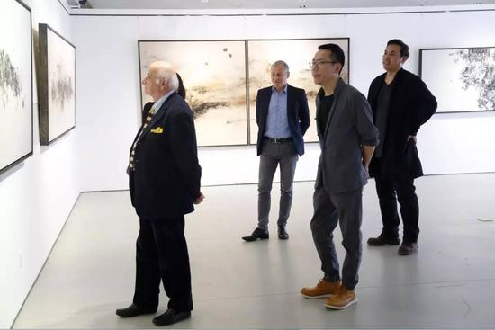 艺术家罗志毅（右二）与嘉宾交流作品