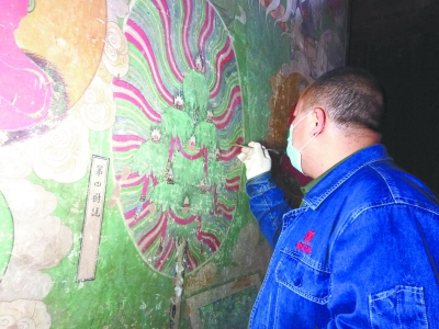 壁画修复小组工作人员在清理壁画    龚正龙 摄.