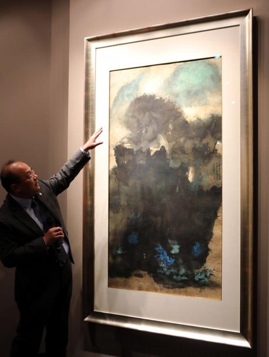 5月25日,佳士得香港的专家在2017年春拍预展上向观众介绍焦点拍品张大千的作品《云山古寺》。新华社记者 李鹏摄