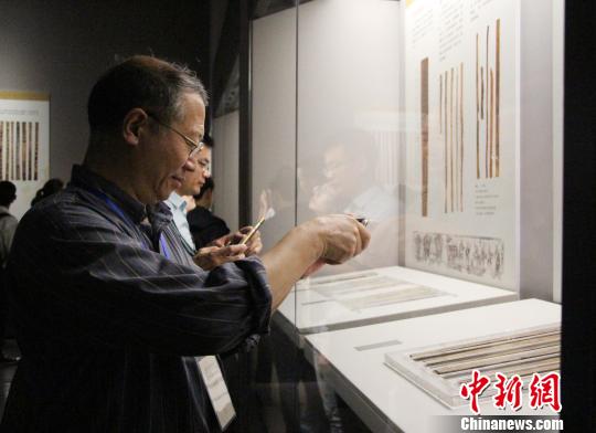 图为参展观众在中国简帛文化展上观看和拍摄简帛文物。　赵晓　摄