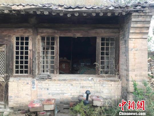 寺庙院内杂草丛生,庙内摆放着杂物和几口棺材,一副萧条景象。 胡健 摄