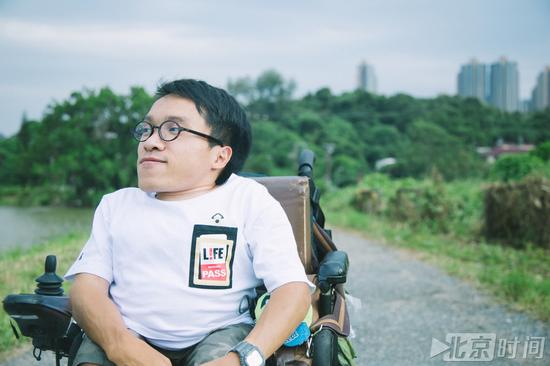 图：独立摄影师郑启文患有SEMD骨骼遗传病，只能坐着电动轮椅外出拍摄