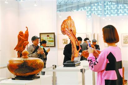 在艺博会上海自贸区特展“艺术之路”展区，观众欣赏木雕作品《荷叶》。本报记者蒋迪雯摄