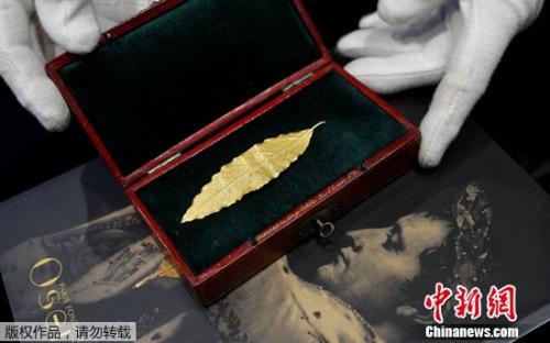 拍卖师展示一片黄金月桂叶,这片金叶子曾是拿破仑加冕礼皇冠上的几十片金叶子之一。