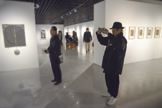 “八三年阶段绘画实验展览”参展艺术家方昉在展厅观画并拍摄做留念