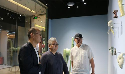 展览现场参展艺术家于凡、谭勋与会空间负责人陶伟光在观看作品