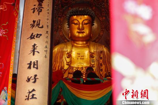 信众在佛台上为大雄宝殿圣像装金。 张亨伟 摄