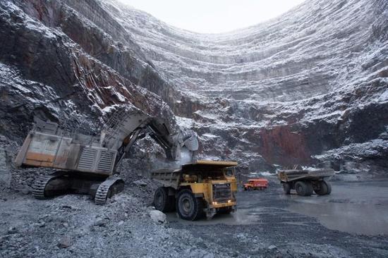 俄罗斯乌达奇内的露天钻石矿，一辆挖掘机正往卡车上装载钻石原石