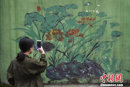 图为“牛皮癣”墙壁上的画作吸引市民拍照留念。 周毅 摄