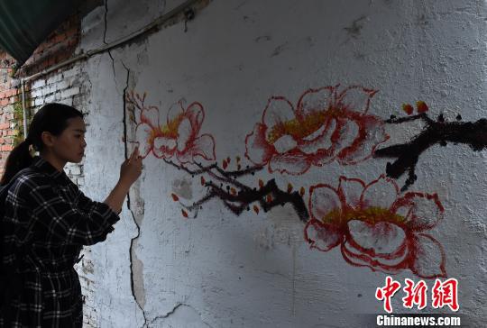 图为环卫工人利用铲掉“牛皮癣”的墙壁作画,吸引市民驻足。 周毅 摄