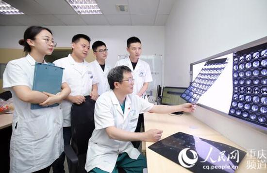 江跃全与同事研究患者病情。李太杰 摄