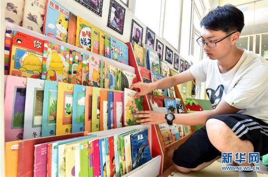 陈叙良为小朋友们整理图书(9月4日摄)。新华社发(庄文斌 摄)