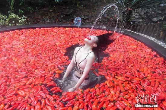 　　一位挑战者从铺满辣椒的温泉池中起身。 
