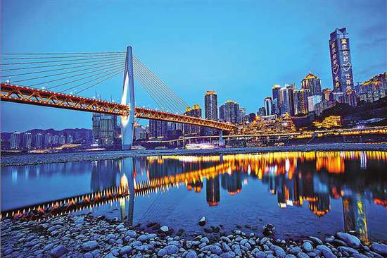 夜色中,千厮门大桥、洪崖洞和高层建筑倒映在嘉陵江江面,美轮美奂。 (本报资料图片)