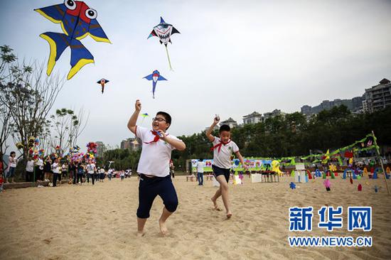 孩子们在阳光沙滩放风筝。新华网发(刘兴敏 摄)