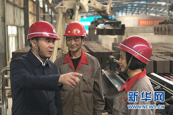 在重庆信奇建材机械制造有限公司机器人操作车间,张信聪(左一)与工人交流废弃物循环再利用。新华网 刘淳 摄