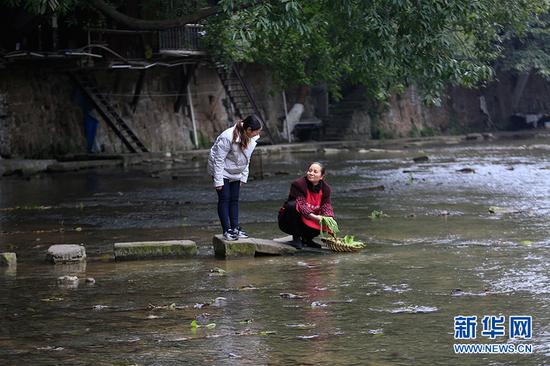  2月26日，在重庆市北碚区金刀峡镇黑水滩河，河长罗玉莲（图左）向洗菜的居民宣传环保知识。新华网发（秦廷富 摄）