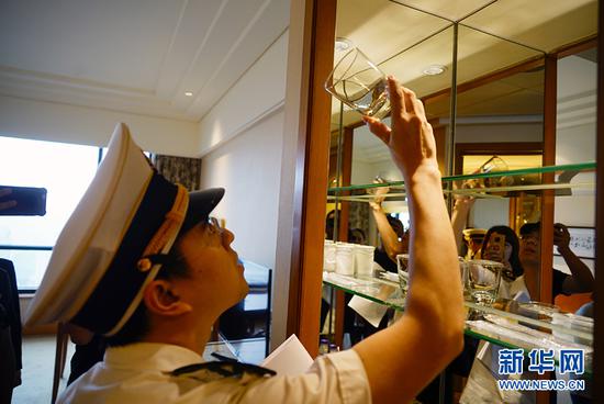 执法人员在仔细检查酒店客房里水杯的卫生清洁情况。新华网 韩梦霖 摄