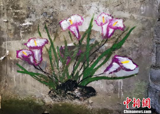 图为环卫工人在铲掉“牛皮癣”的墙壁上作画美化环境。 周毅 摄