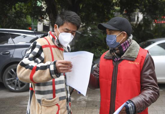 2月3日,重庆市万州区牌楼街道石峰社区志愿者(右)向居民发送疫情防控宣传资料。新华社记者王全超摄