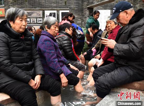 图为市民在露天温泉泡脚驱寒。 周毅 摄