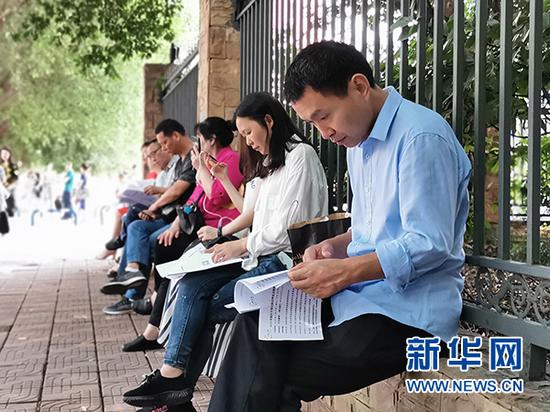 坐在路边等考生的家长。新华网发(潘亚芬 摄)