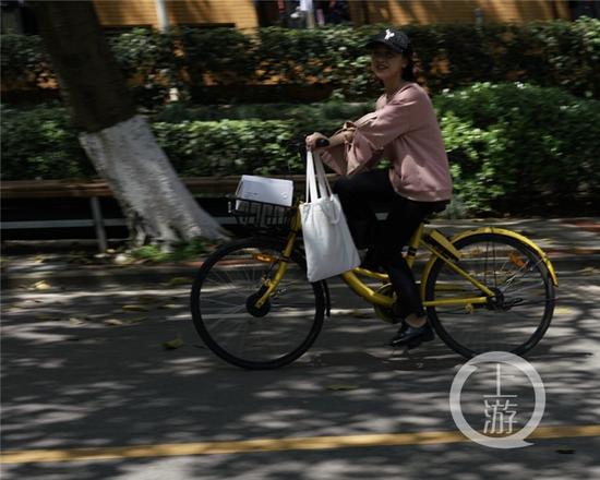 △大学城,学生在树荫下骑行。