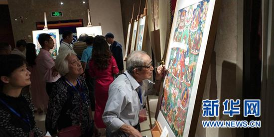 “五彩祥云——西藏唐卡艺术重庆首展”现场,游客仔细观赏展览作品。新华网发(主办方供图)