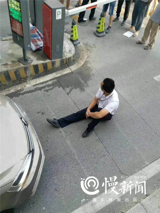 为防止小车强行冲卡,小区物管经理以身挡车。业主提供