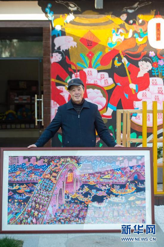 嘉兴市秀洲区油车港镇胜丰村村民张金泉与自己的画作《国泰民安》合影(2020年12月15日摄)。新华社发(江汉 摄)