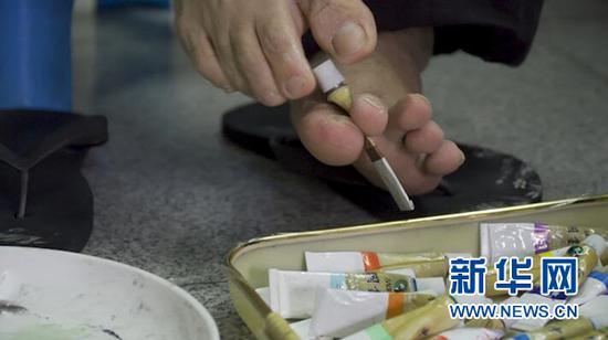 黄国富用脚趾旋转颜料盖。新华网 彭博 摄