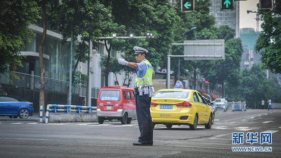7月19日早高峰,邵钢在巨成龙湾十字路口指挥交通。新华网发(南岸公安供图)
