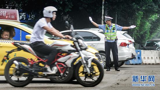 7月19日早高峰,邵钢在巨成龙湾十字路口指挥车辆通过。新华网发(南岸公安供图)