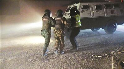 武警官兵帮被困者戴上头盔,在飞沙走石中将其引导至装甲车旁 供图/武警新疆总队克拉玛依支队