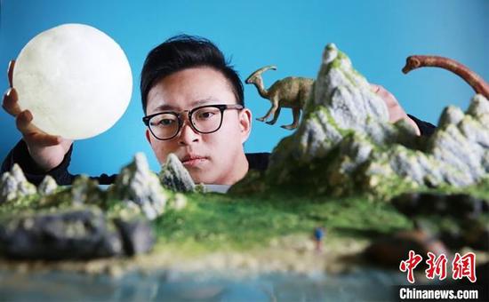 图为丁洲在做微缩摄影作品布景。受访者供图