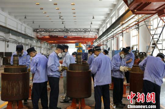  图为电枢检修工清理牵引电机电枢表面绝缘漆，周围环境温度高达50℃左右。　李富彬 摄