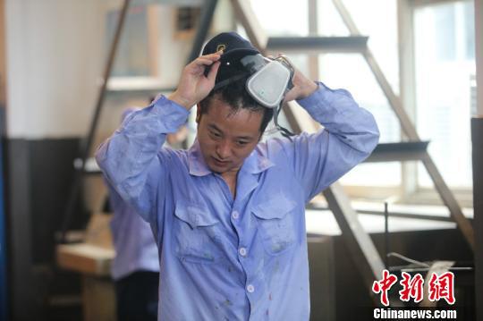 图为摘下防毒面罩准备休息的电枢检修工。高温天气，进入维修车间不到5分钟，电枢检修工全身基本会湿透。　李富彬 摄