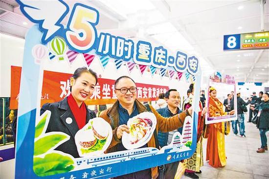 12月6日,乘客在重庆北—西安北的首发动车前合影留念。