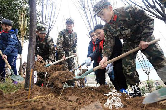 武警官兵和学生一起植树。记者 李文科 摄