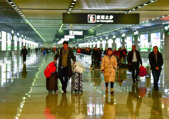 △2月12日,重庆西站出站通道内,旅客们走向出站口