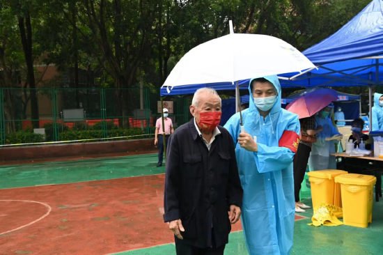 礼嘉街道白马社区采样点,现场工作人员为老人撑伞。(蓝天 摄)