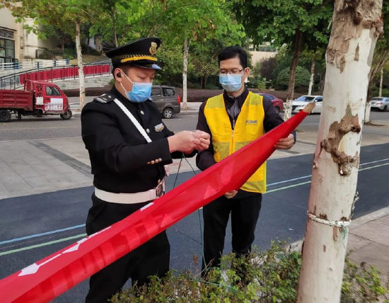 和物业一起悬挂宣传横幅的曹忠鲁(右一)。康美街道供图