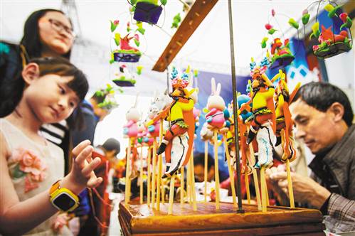 4月18日,在解放碑步行街,剪纸、面塑、糖画等非遗传承人在现场创作