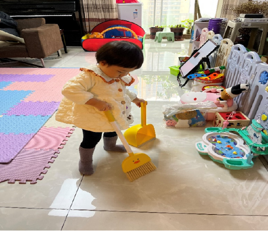 图为女儿多米在家收拾玩具，打扫卫生