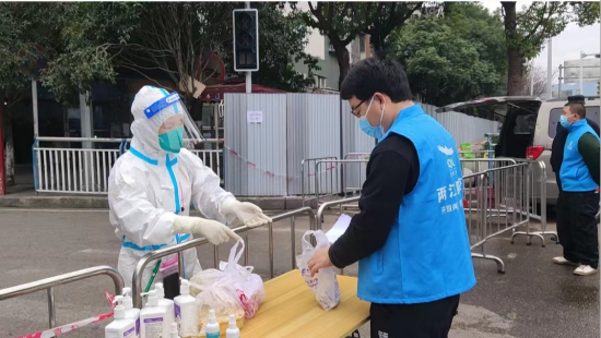 (工作人员在管控区卡点取到居民的购药清单。)