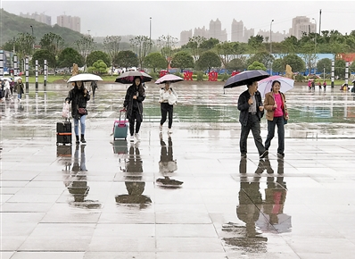 重庆火车北站广场,雨中来来往往的人群。 本报记者 杨新宇 摄