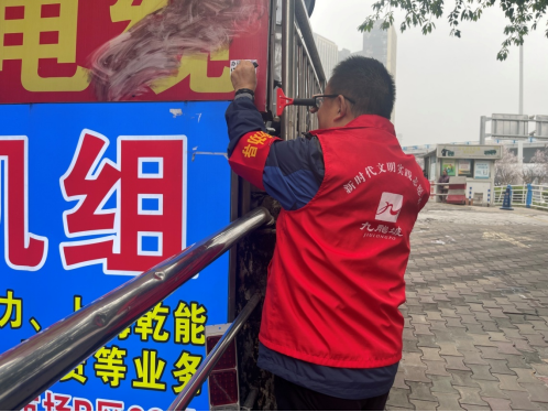 (机关第一党支部党员志愿者在陈家坪汽车站附近清理墙面)
